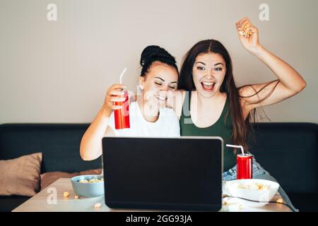 Mädchen sehen sich eine Live-Übertragung auf einem Laptop an und freuen sich über den Sieg ihres Teams Stockfoto