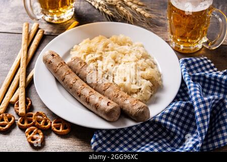 Bratwurst, Sauerkraut, Brezeln und Bier auf Holztisch Stockfoto