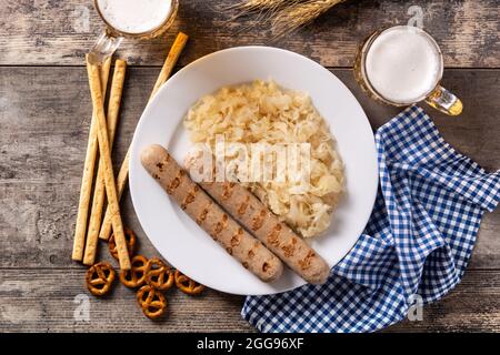 Bratwurst, Sauerkraut, Brezeln und Bier auf Holztisch Stockfoto