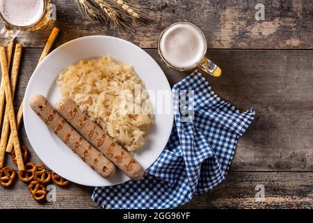 Bratwurst, Sauerkraut, Brezeln und Bier auf Holztisch Stockfoto