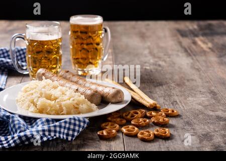 Bratwurst, Sauerkraut, Brezeln und Bier auf Holztisch Stockfoto