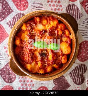 Gnocchi alla Sorrentina, italienische Kartoffelknödel in Tomatensauce, mit Mozzarella-Käse in einer Terrakotta-Schale geriebt. Stockfoto