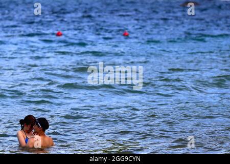 Keelung, Taipei, Taiwan. August 2021. Ein Paar schwimmt im Meer in der Nähe eines Strandes in Keelung, wo die Menschenmenge kontrolliert wird, da Taiwan laut dem taiwanesischen CDC nur 3 lokal erworbene Fälle und null Todesfälle meldet. Nachdem die Versammlungen und Schwimmaktivitäten wieder aufgenommen wurden, verzeichnet die selbstregierte Insel seit ihrem schweren Ausbruch im Mai einen Abwärtstrend bei einheimischen Covid-Infektionen und -Todesfällen, indem sie Impfstoffe für AstraZeneca, Medigen und Moderna zur Verfügung stellt, während sie Impfstoffspenden aus den USA, Japan, Litauen und der Tschechischen Republik erhält. Angesichts der zunehmenden militärischen Bedrohungen Chinas. (Kredit Imag Stockfoto