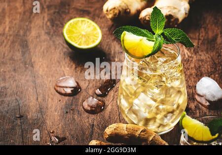 Klassische Ginger Ale Cocktails mit Bier, Limette, Zitrone und Minze in Glas auf Holztisch, negativer Raum Stockfoto