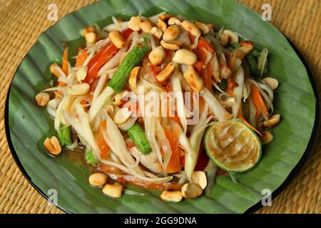 Nahaufnahme Papaya-Salat auf Bananenblatt. Stock-Foto isolieren auf braunen gewebten Matte Hintergrund Draufsicht Stockfoto