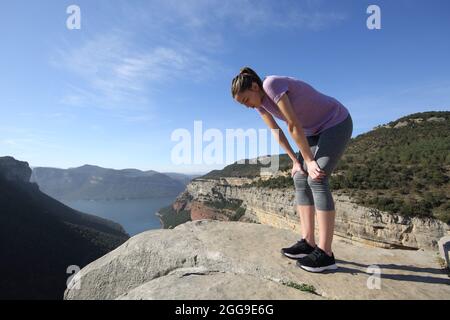 Erschöpfter Läufer, der sich nach dem Sport auf einer Klippe im Berg ausruhte Stockfoto