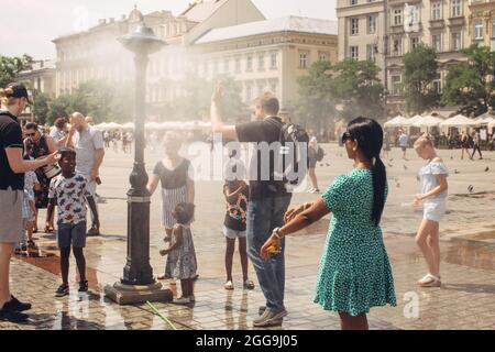 KRAKAU, POLEN - 21. Juli 2019: Vernebelungswassersystem für die Kühlung Arbeiten auf einem Hauptplatz von Krakau in heißen Sommertagen, Touristen in der Nähe streuen Vernebeln Stockfoto