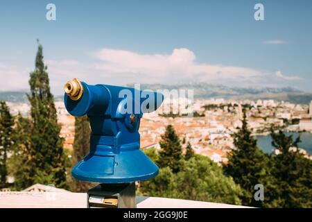 Touristischer Blick auf eine Küstenstadt vom Aussichtspunkt auf dem Hügel mit dem münzbetriebenen Spyglass, selektiver Fokus auf Okular Stockfoto