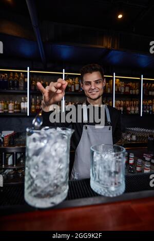 Barkeeper rührt Eiswürfel in Cocktailglas mit Löffel Stockfoto