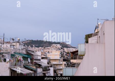 Stadtbild eines Wohngebiets in Athen bei Abendlicht. Stadtarchitektur. Berg im Hintergrund. Stockfoto