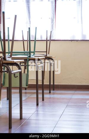 Kinderschulstühle, die auf den Schreibtischen angehoben wurden.das Foto wurde im Hochformat aufgenommen. Stockfoto