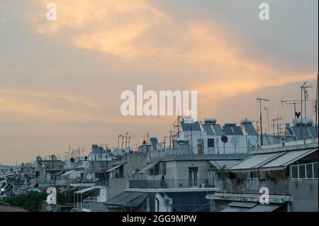 Stadtbild eines Wohngebiets in Athen bei Abendlicht. Stadtarchitektur. Sonnenkollektoren und Satellitenschüsseln auf dem Dach. Stockfoto