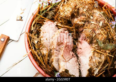 Köstliches Fleisch in frischem Heu gebraten. Gebackenes Schweinefleisch in würzigen Kräutern.Herbstfutter Stockfoto