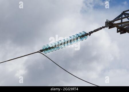 Glasisolator an Hochspannungsleitung gegen blauen Himmel Stockfoto