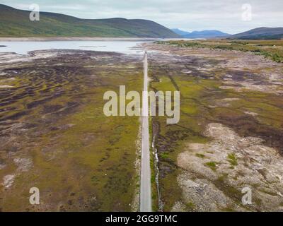 Garve, Schottland, Großbritannien. 30. August 2021.der niedrige Wasserstand im Stausee von Loch Glascarnoch bei Garve hat bisher verborgene Strukturen enthüllt, darunter eine alte Straße, eine Brücke und Telegrafenmasten. Die alte Straße war die Hauptroute von Ullapool nach Dingwall, bis die aktuelle neue Straße neben dem Stausee gebaut wurde. Der Stausee in Glen Glascarnoch wurde in den 1950er Jahren als Teil des Wasserkraftwerks Conon gegründet. Iain Masterton/Alamy Live News. Stockfoto