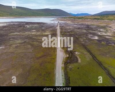 Garve, Schottland, Großbritannien. 30. August 2021.der niedrige Wasserstand im Stausee von Loch Glascarnoch bei Garve hat bisher verborgene Strukturen enthüllt, darunter eine alte Straße, eine Brücke und Telegrafenmasten. Die alte Straße war die Hauptroute von Ullapool nach Dingwall, bis die aktuelle neue Straße neben dem Stausee gebaut wurde. Der Stausee in Glen Glascarnoch wurde in den 1950er Jahren als Teil des Wasserkraftwerks Conon gegründet. Iain Masterton/Alamy Live News. Stockfoto