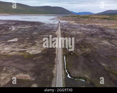 Garve, Schottland, Großbritannien. 30. August 2021.der niedrige Wasserstand im Stausee von Loch Glascarnoch bei Garve hat bisher verborgene Strukturen enthüllt, darunter eine alte Straße, eine Brücke und Telegrafenmasten. Die alte Straße war die Hauptroute von Ullapool nach Dingwall, bis die aktuelle neue Straße neben dem Stausee gebaut wurde. Der Stausee in Glen Glascarnoch wurde in den 1950er Jahren als Teil des Wasserkraftwerks Conon gegründet. Iain Masterton/Alamy Live News. Stockfoto