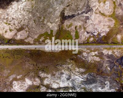 Garve, Schottland, Großbritannien. 30. August 2021.der niedrige Wasserstand im Stausee von Loch Glascarnoch bei Garve hat bisher verborgene Strukturen enthüllt, darunter eine alte Straße, eine Brücke und Telegrafenmasten. Die alte Straße war die Hauptroute von Ullapool nach Dingwall, bis die aktuelle neue Straße neben dem Stausee gebaut wurde. Der Stausee in Glen Glascarnoch wurde in den 1950er Jahren als Teil des Wasserkraftwerks Conon gegründet. Iain Masterton/Alamy Live News. Stockfoto