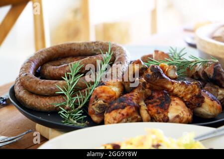 Grillen Sie Fleisch, Huhn und Boerewors auf Teller, fertig zum Essen mit Salat und Mais Stockfoto