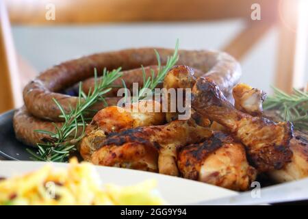 Grillen Sie Fleisch, Huhn und Boerewors auf Teller, fertig zum Essen mit Salat und Mais Stockfoto