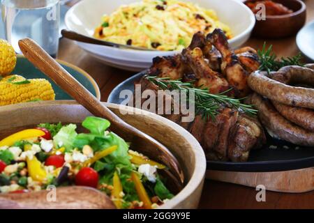 Grillen Sie Fleisch, Huhn und Boerewors auf Teller, fertig zum Essen mit Salat und Mais Stockfoto