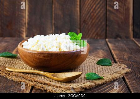 Schüssel mit Hüttenkäse auf Holzhintergrund. Frischer hausgemachter Hüttenkäse Stockfoto