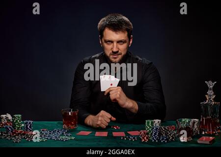Bärtiger Casino Spieler Mann, der Poker auf dem grünen Tisch spielt Stockfoto