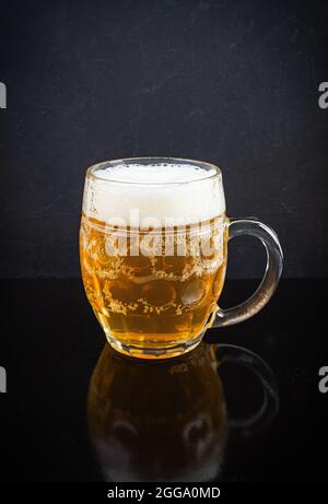 Becher helles Bier auf dunklem Hintergrund. Gebraut ungefiltertes Bier Stockfoto