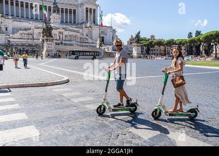 ROM, ITALIEN, GROSSBRITANNIEN. August 2021. Menschen, die an einem heißen Tag in Rom auf der Piazza Venezia einen Elektroroller fahren. Elektroroller sind in der römischen Hauptstadt populär geworden und werden regelmäßig als Mobilitätstransport eingesetzt. Kredit: amer ghazzal/Alamy Live Nachrichten Stockfoto