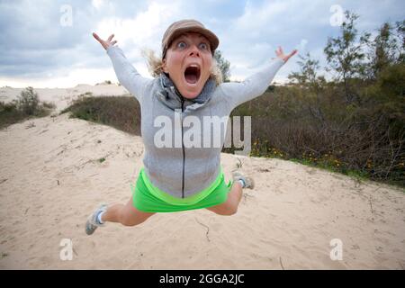 Die junge Frau zieht ein Gesicht, während sie in die Luft springt Stockfoto