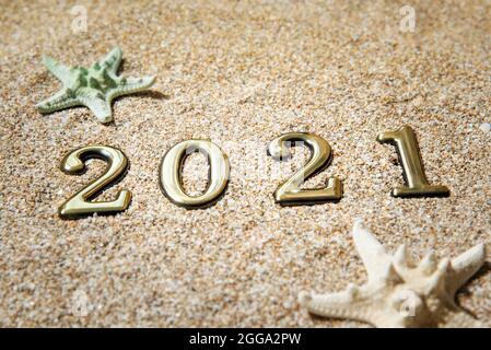 Goldene Zahlen 2021 und Seesterne auf dem Sand am Meer. Stockfoto