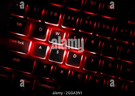 Rote Computertastatur mit Hintergrundbeleuchtung. Nahaufnahme der hervorgehobenen Standardtasten in Spielen, die mit Bewegungen verbunden sind. Professionelle Computerspiele spielen, Stockfoto