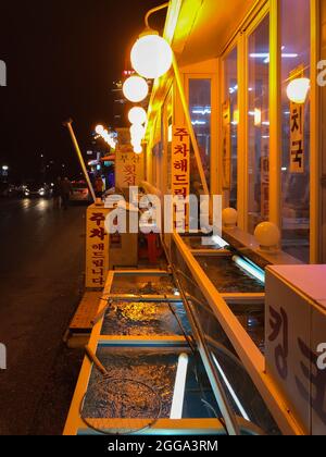 Gangneung, Südkorea - 16. Februar 2018: Beleuchtete Straße mit Restaurants neben dem Gyeongpo Strand in Gangmun-dong, nachts Stockfoto