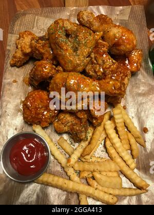 Gebratenes Huhn mit heißer Sauce und Pommes auf Papier serviert Stockfoto