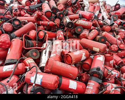 Alte Feuerlöscher werden zum Recycling und zur Entsorgung gesammelt. Gebrauchte Pulver- und Schaumlöschgeräte in einer Deponie. Plastikverschmutzung und Abfall Re Stockfoto