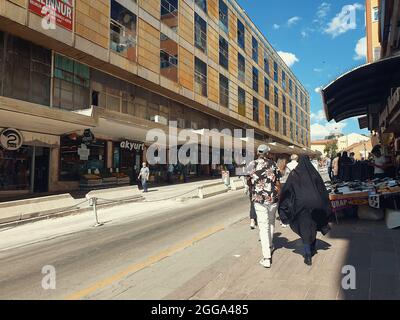 Mann in Sportkleidung und Frau in Hijab beim Spaziergang in der Anafartalar Straße im Ulus-Viertel in Ankara, Türkei. Stockfoto