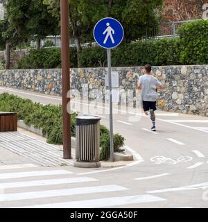 zeichen einer Fußgängerzone neben einem Radweg am Ufer einer Küstenstadt mit jungen Läufern Stockfoto