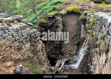 Die Überreste des eingestürzten Blakethwaite-Staudamms, der in den 1830er Jahren erbaut wurde, um Wasser für die Minen in Gunnerside Gill, Swaledale, Yorkshire Dale, zu speichern Stockfoto