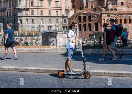 ROM, ITALIEN, GROSSBRITANNIEN. August 2021. Menschen, die an einem heißen Tag in Rom auf der Via dei Fori Imperiali mit einem Elektroroller fahren. Elektroroller sind in der römischen Hauptstadt populär geworden und werden regelmäßig als Mobilitätstransport eingesetzt. Kredit: amer ghazzal/Alamy Live Nachrichten Stockfoto