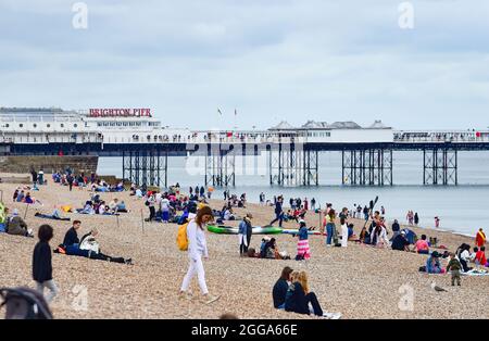 Brighton UK 30. August 2021 - Besucher am Brighton Strand in der Nähe des Piers trotz des bewölkten Feiertagswetters im August. : Credit Simon Dack / Alamy Live News Stockfoto