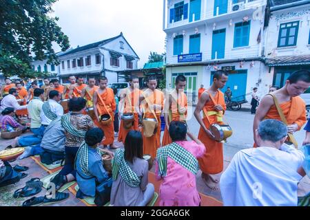 Luang Prabang, Laos - 5. NOVEMBER 2011: Buddhistische Mönche und Novizen erhalten während ihrer morgendlichen Almosen Nahrung. Luang Prabang. Stockfoto