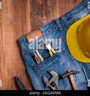 Draufsicht Designkonzept des Labor Day mit Arbeitswerkzeugen und Jeans auf Holztischhintergrund. Stockfoto