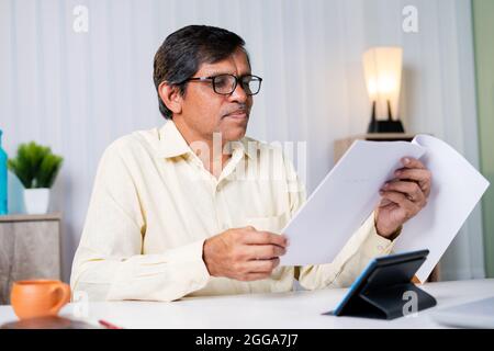 Geschäftsmann beim Prüfen oder Lesen von Steuer- oder Vertragsunterlagen während der Arbeit im Büro. Stockfoto