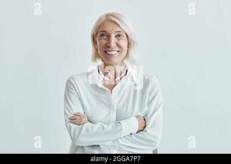 Waist-up-Porträt der eleganten reifen Frau posiert selbstbewusst mit Armen vor weißem Hintergrund gekreuzt, kopieren Raum Stockfoto