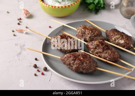 Traditionelles Gericht der arabischen Küche, gegrilltes Hackfleisch-Shish-Kebab auf Holzspießen auf grauem Teller Stockfoto