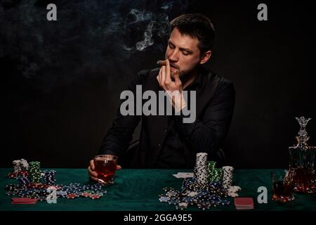 Bärtiger Casino Spieler Mann, der Poker auf dem grünen Tisch spielt Stockfoto