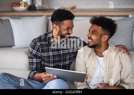 Junge Studentenbrüder in der Küche zuhause, mit Tablet und lachen. Stockfoto