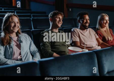 Junge Leute mit Popcorn im Kino, sehen sich Thriller-Film an. Stockfoto