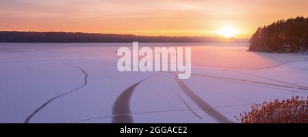 Familien-Silhouette von vier Personen Eiskunstlauf am gefrorenen See gegen schönen Sonnenuntergang. Aktivitäten im Freien an Wochenenden bei kaltem Wetter. Stockfoto