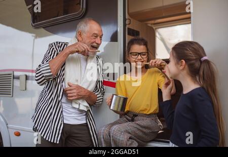 Glückliche kleine Mädchen mit Großvater Zähneputzen von Wohnwagen, Familienurlaub Reise. Stockfoto